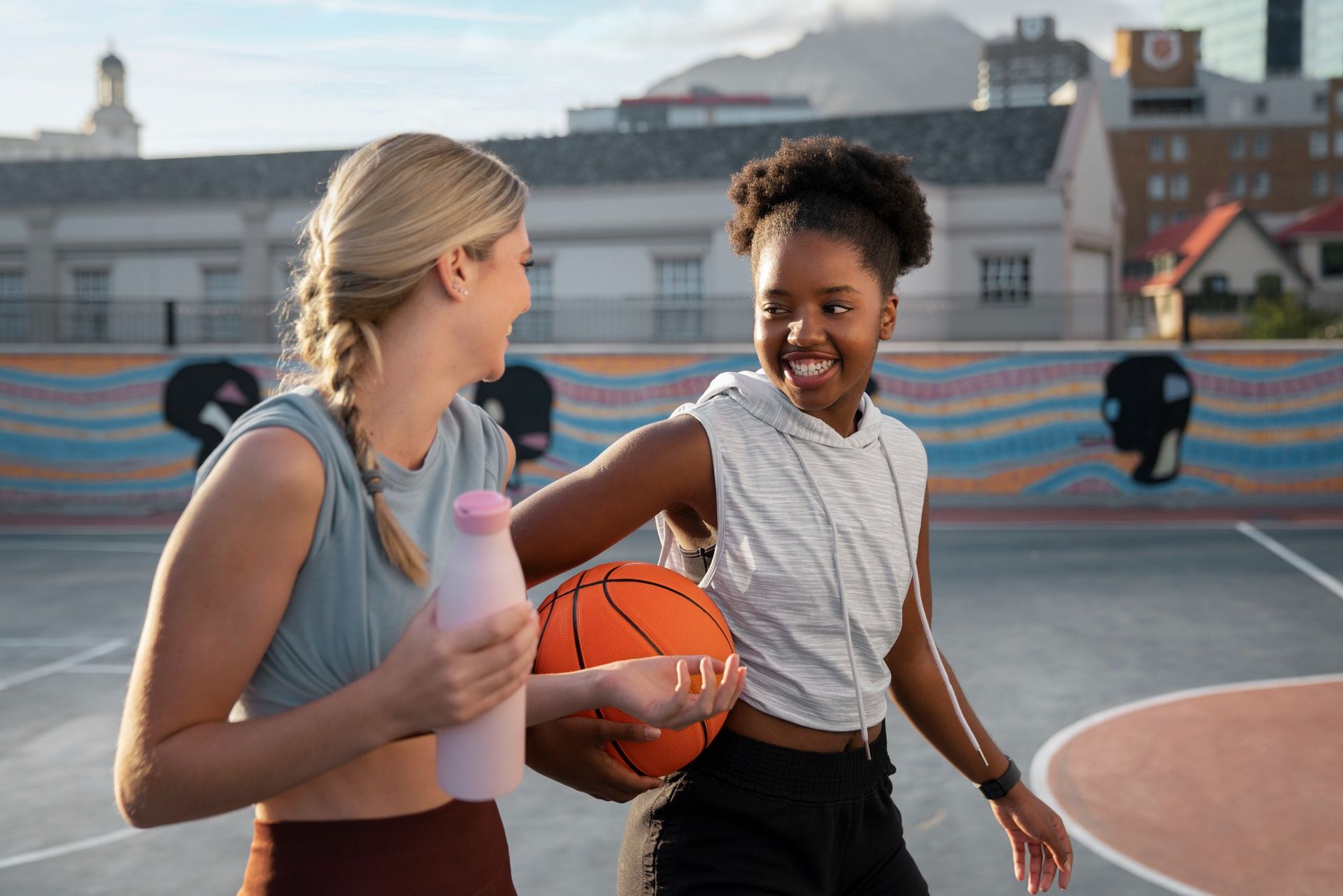 Two women are playing basketball on a court.