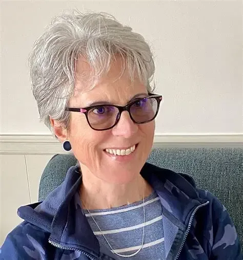 A woman in a suit and collared shirt is smiling for the camera.