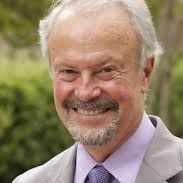 A man with a beard is wearing a suit and tie and smiling.