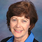 A woman wearing a blue shirt and black jacket smiles for the camera