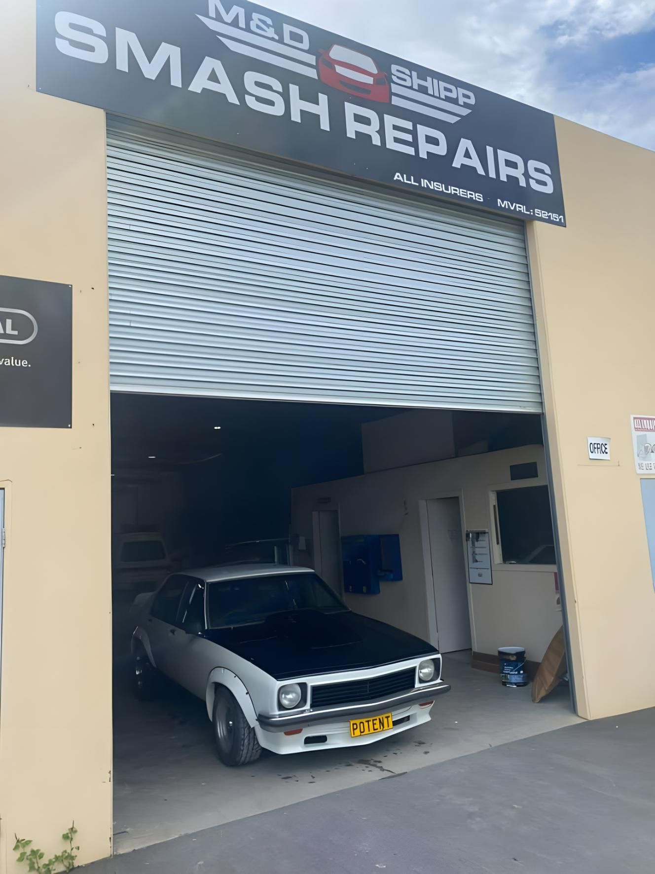 A Car is Parked in Front of a Garage Door — M & D Shipp Smash Repairs In Dubbo, NSW