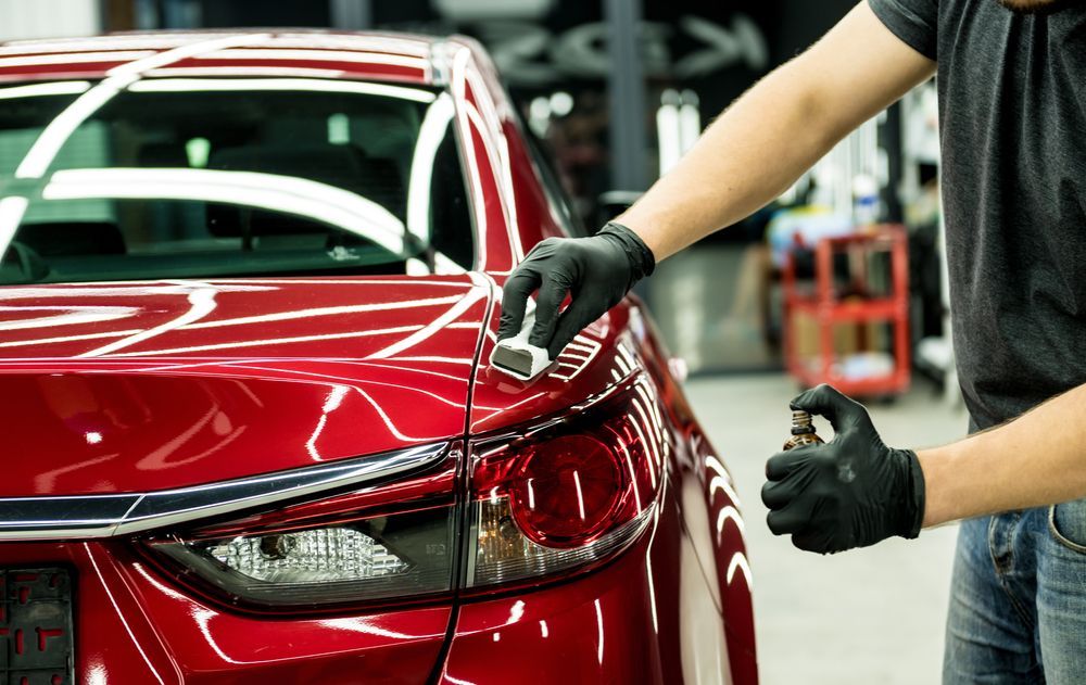 A Man is Polishing a Red Car in a Garage — M & D Shipp Smash Repairs In Dubbo, NSW