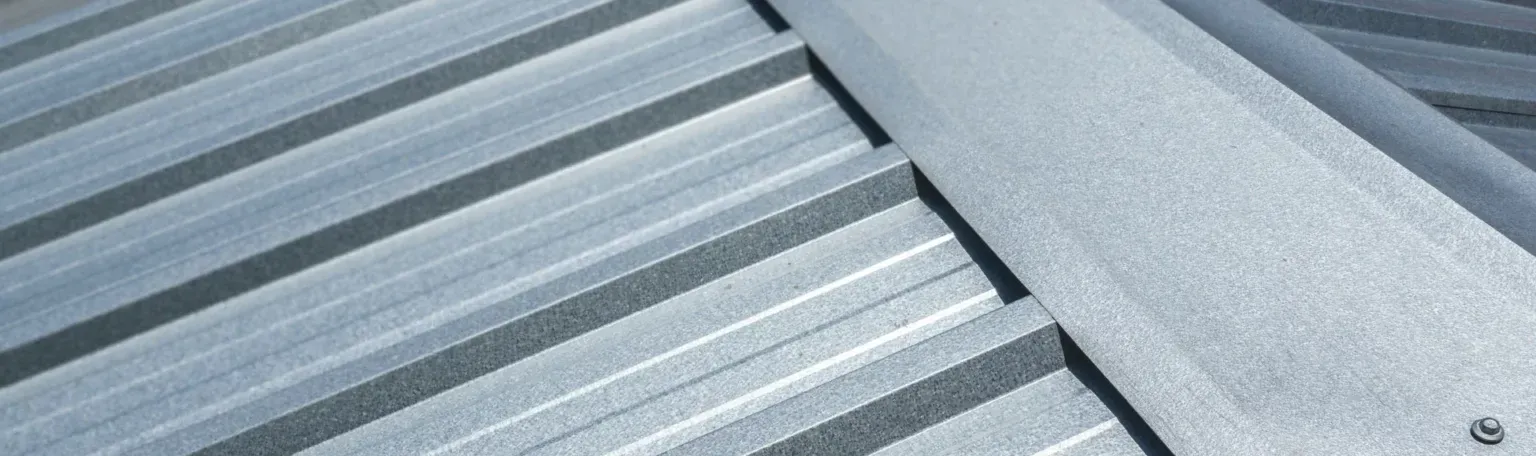 Close-up of a silver metal corrugated roof with a flat, overlapping sheet.