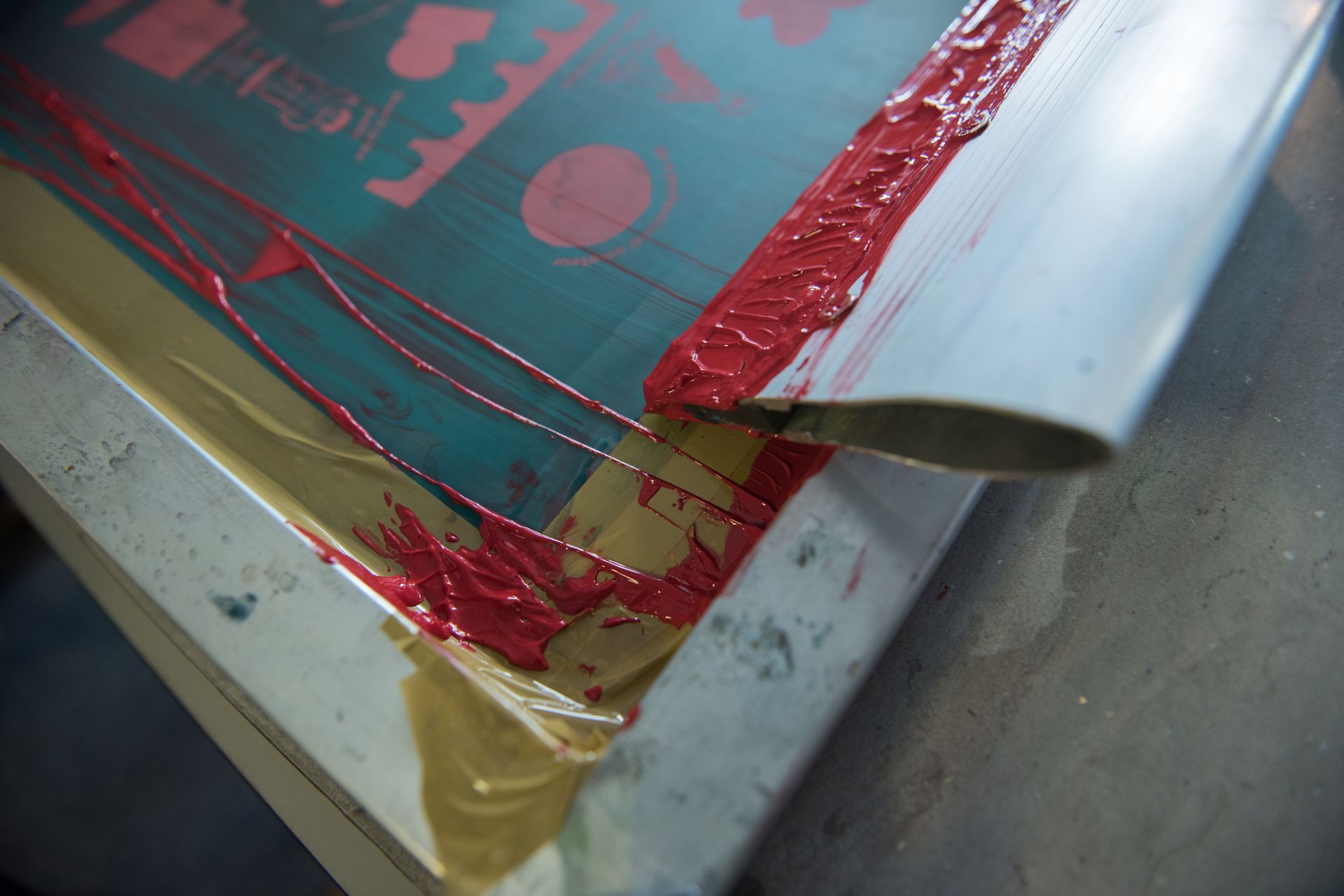 Close-up of a red-screen-printed sheet with a corner peeling on a worktable