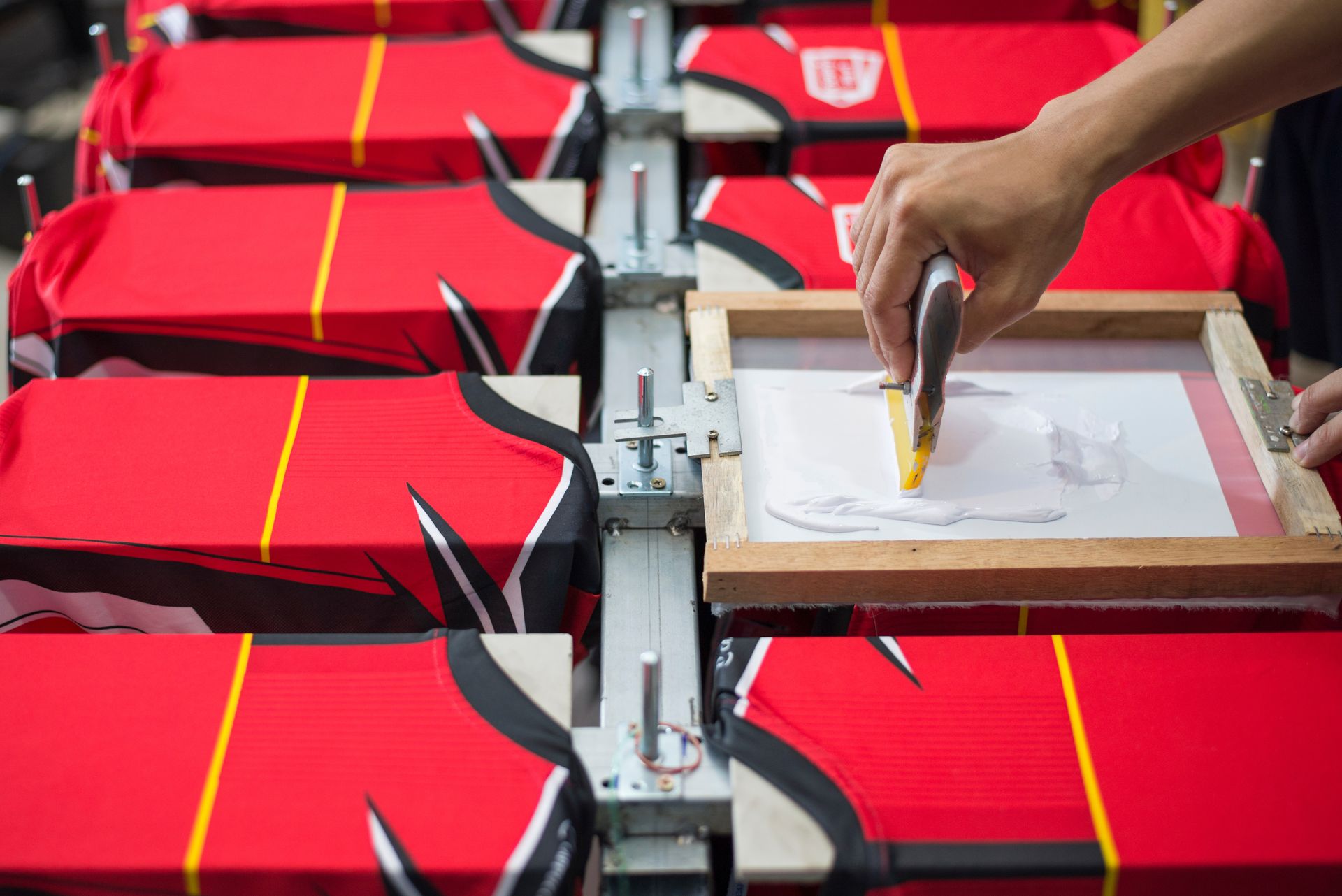 Hand printing red bags on a production line with a screen-printing frame