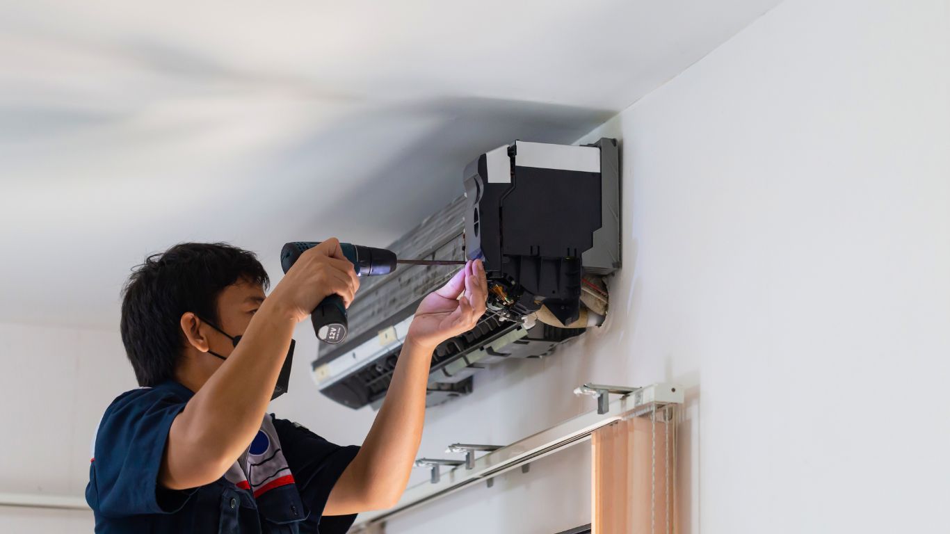 TSC-HVAC - A man is installing an air conditioner on a wall.
