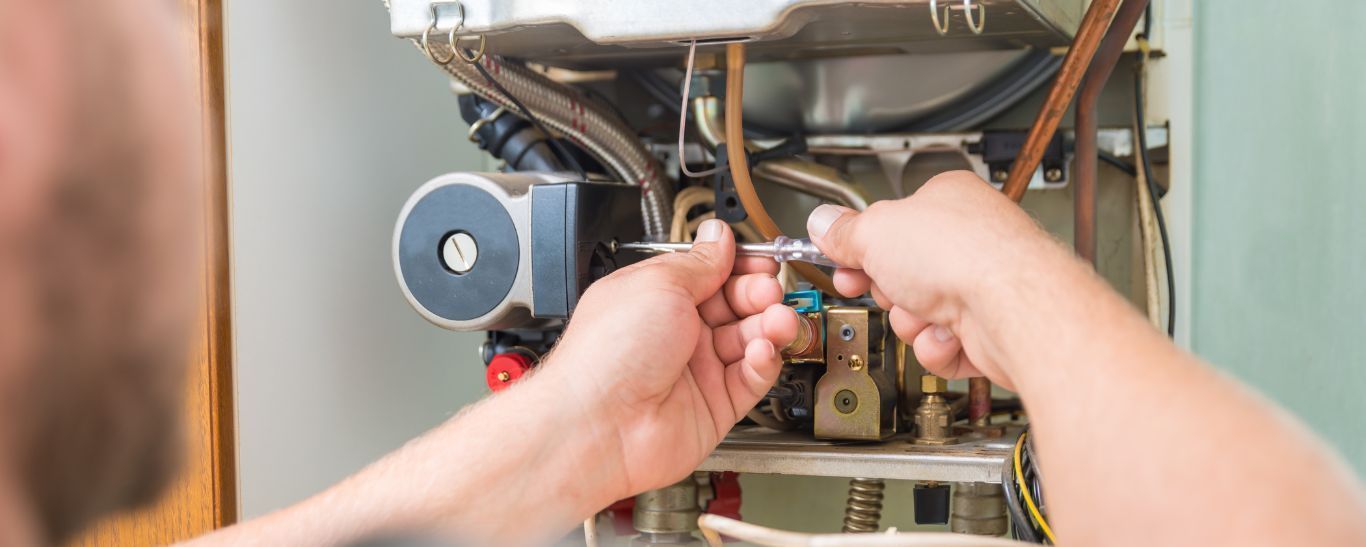 TSC-HVAC - A man is fixing a boiler with a wrench.