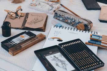 A table topped with notebooks , pencils , pens , and a pencil case.