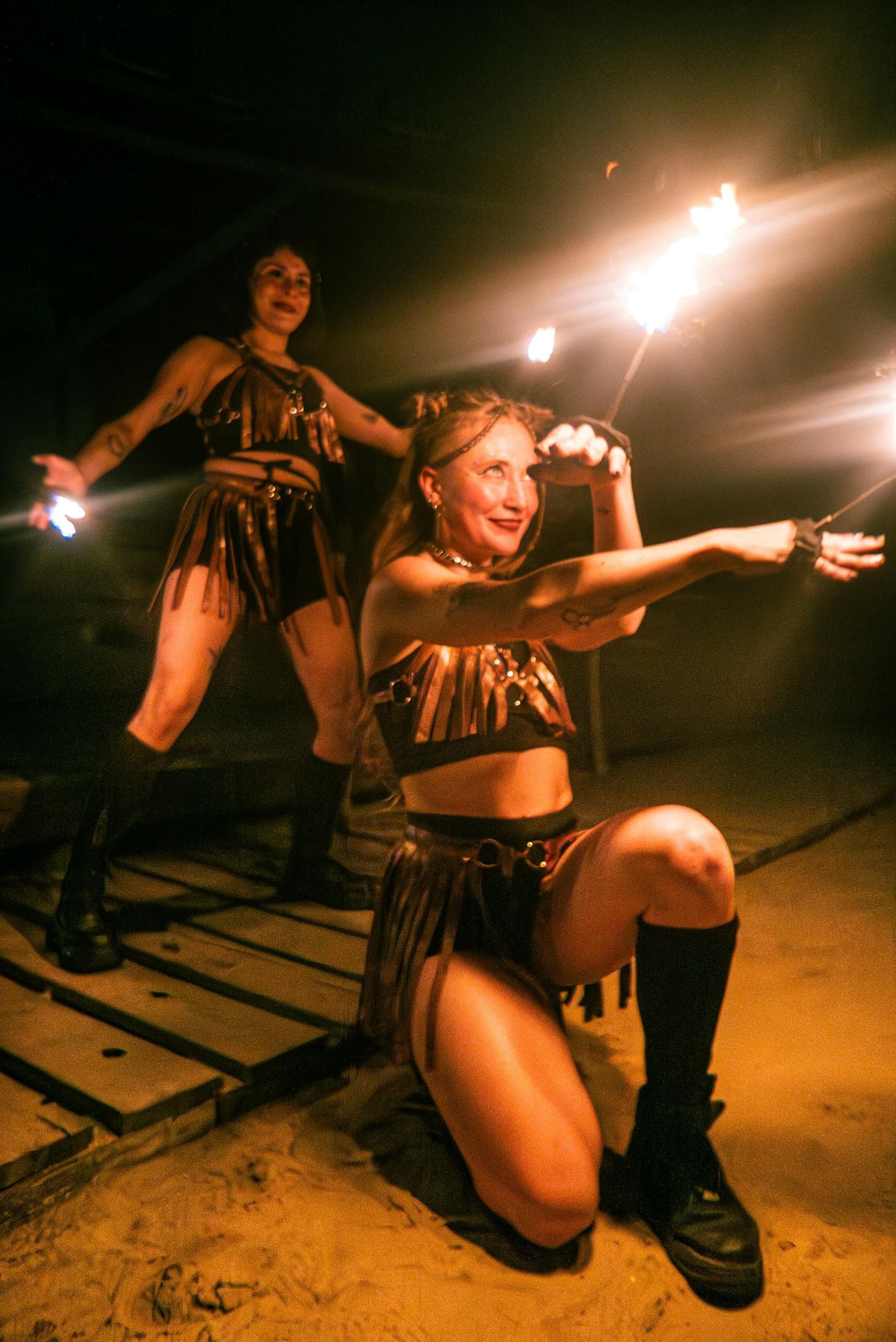 Two women are holding fireworks in their hands in the dark.