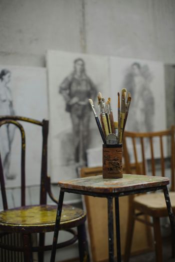 A bunch of brushes are sitting on a table in an art studio.