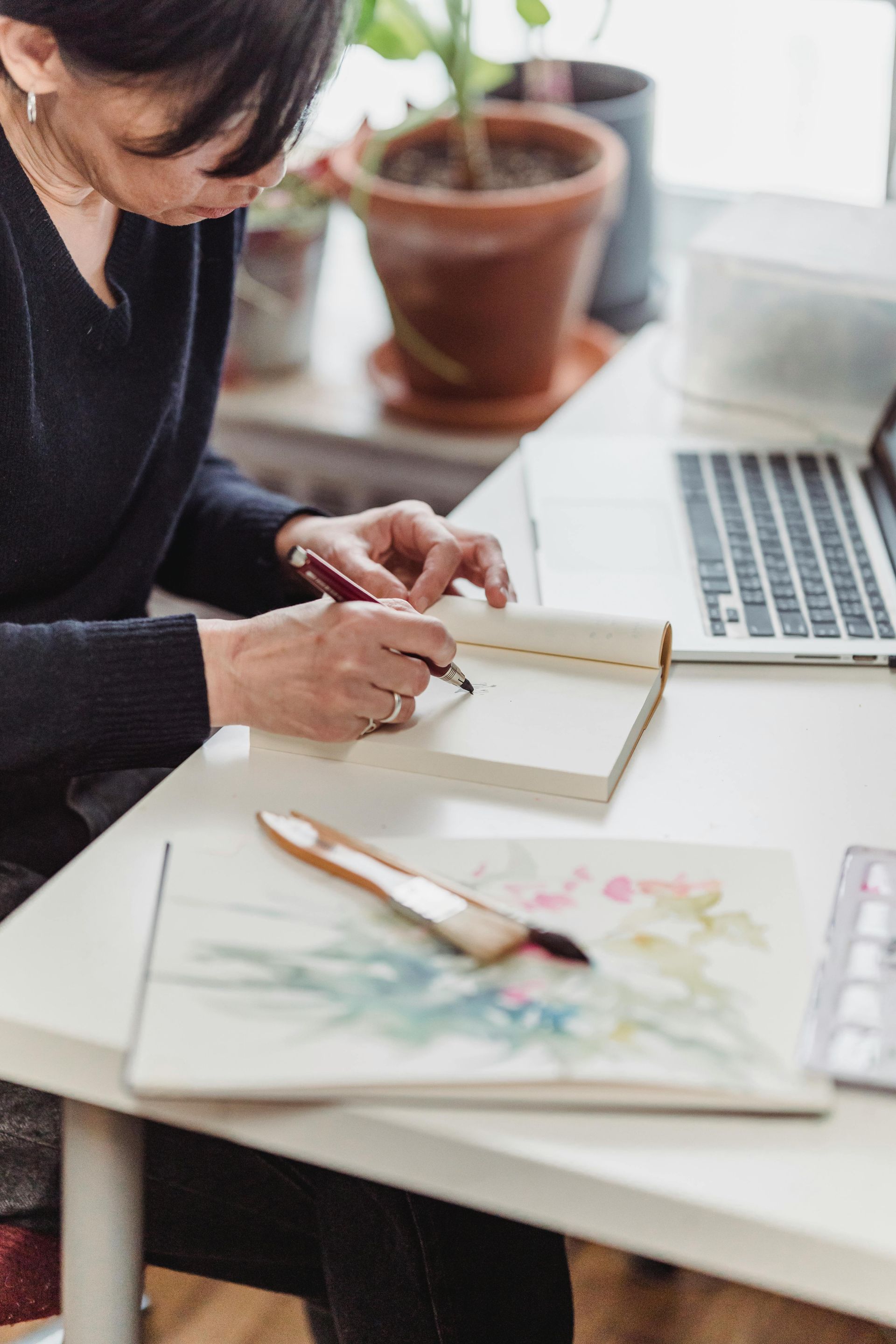 A woman is sitting at a desk writing in a notebook.