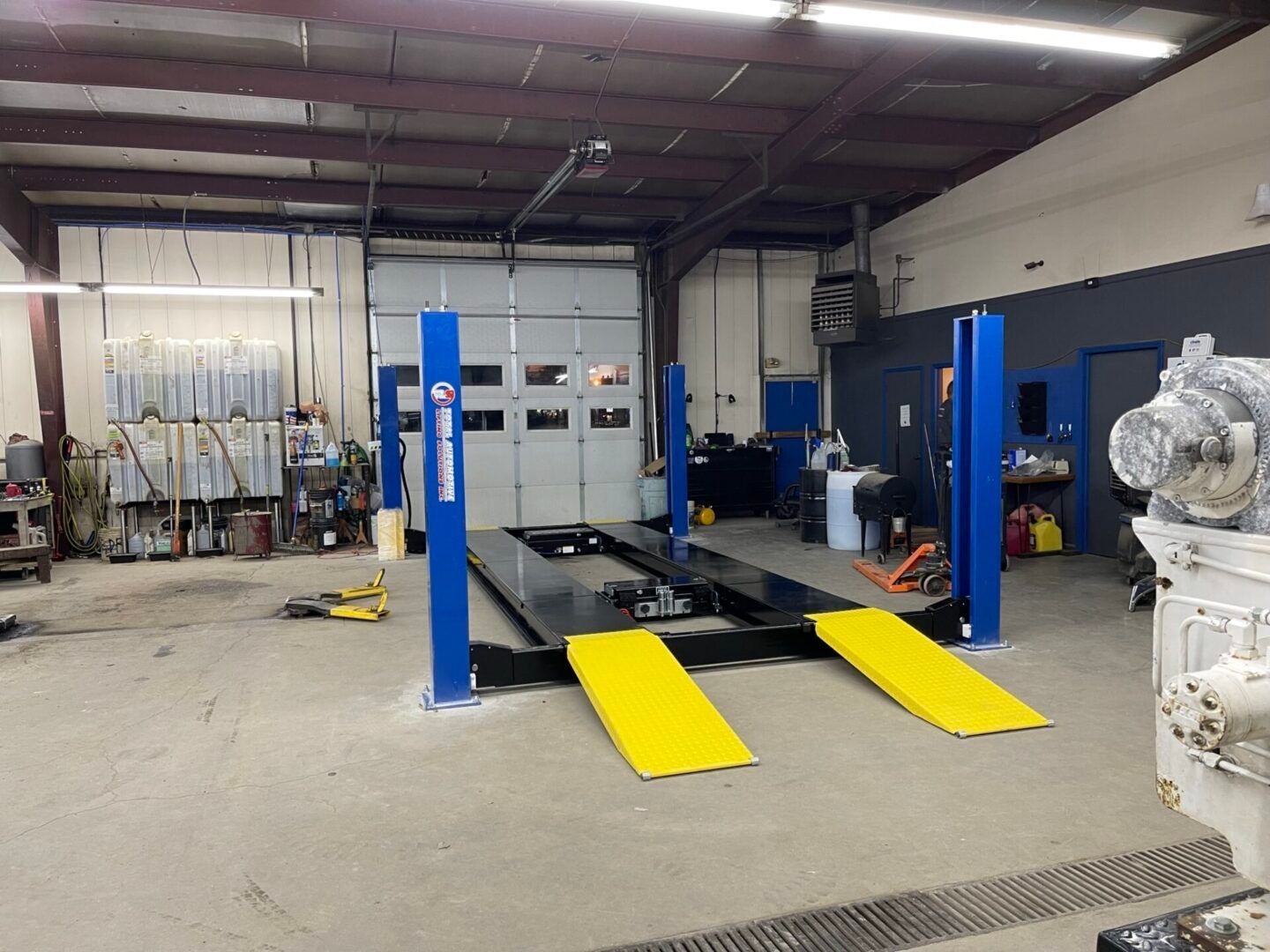 A blue and yellow car lift is in a garage.