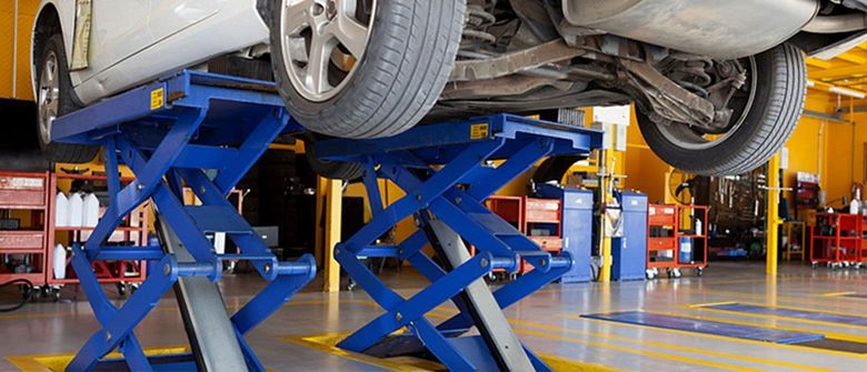 A car is sitting on a lift in a garage.