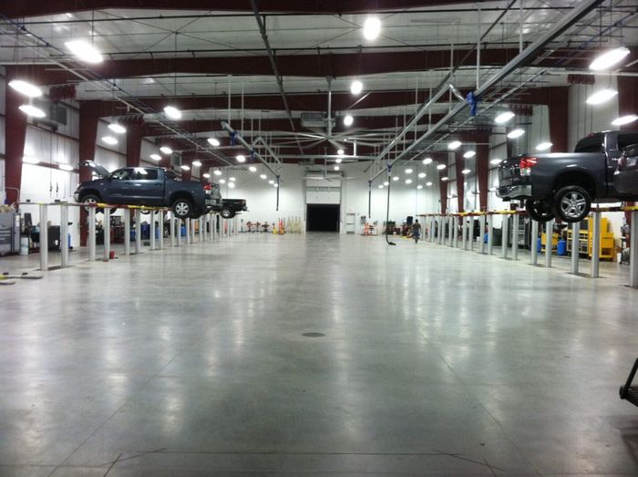 A warehouse with a lot of cars on lifts