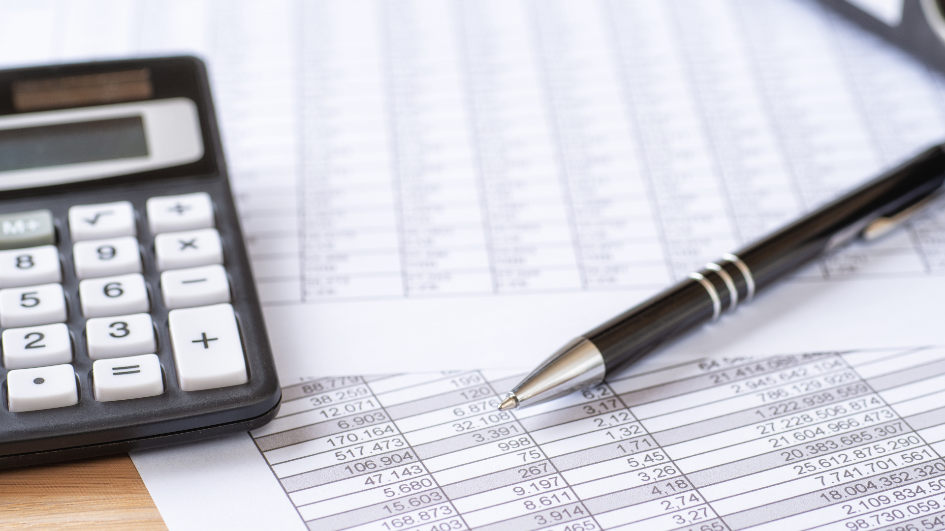 Calculator and pen on a spreadsheet with columns and rows, likely for financial calculations.