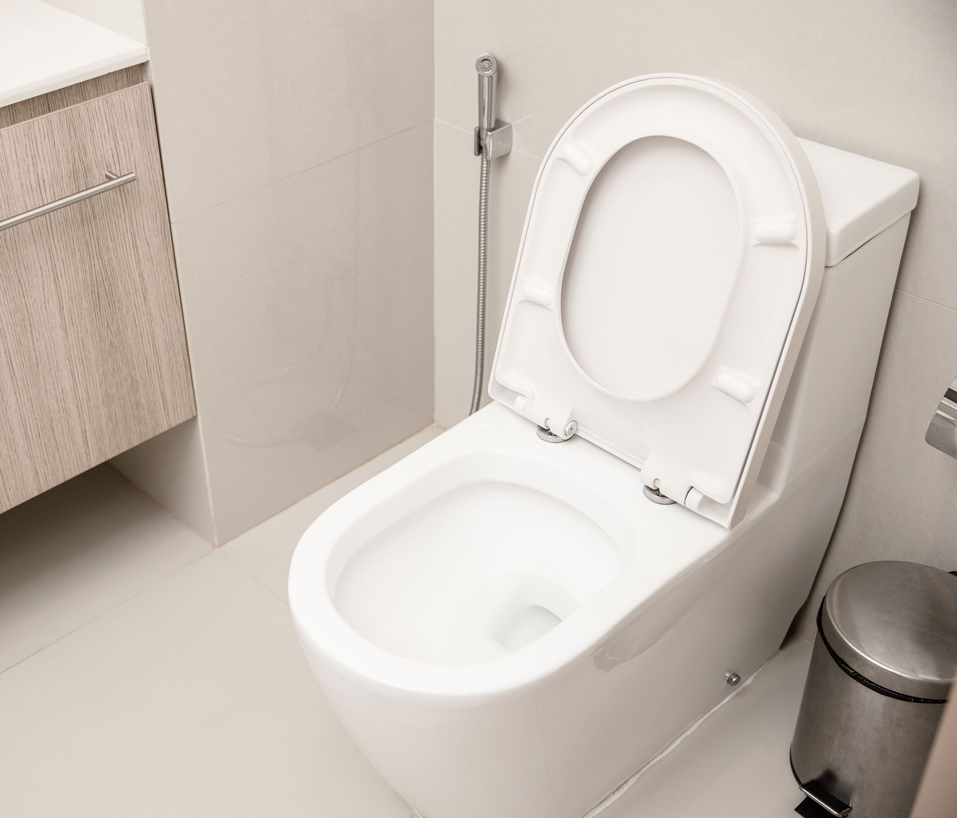 A white toilet is sitting in a bathroom next to a trash can.