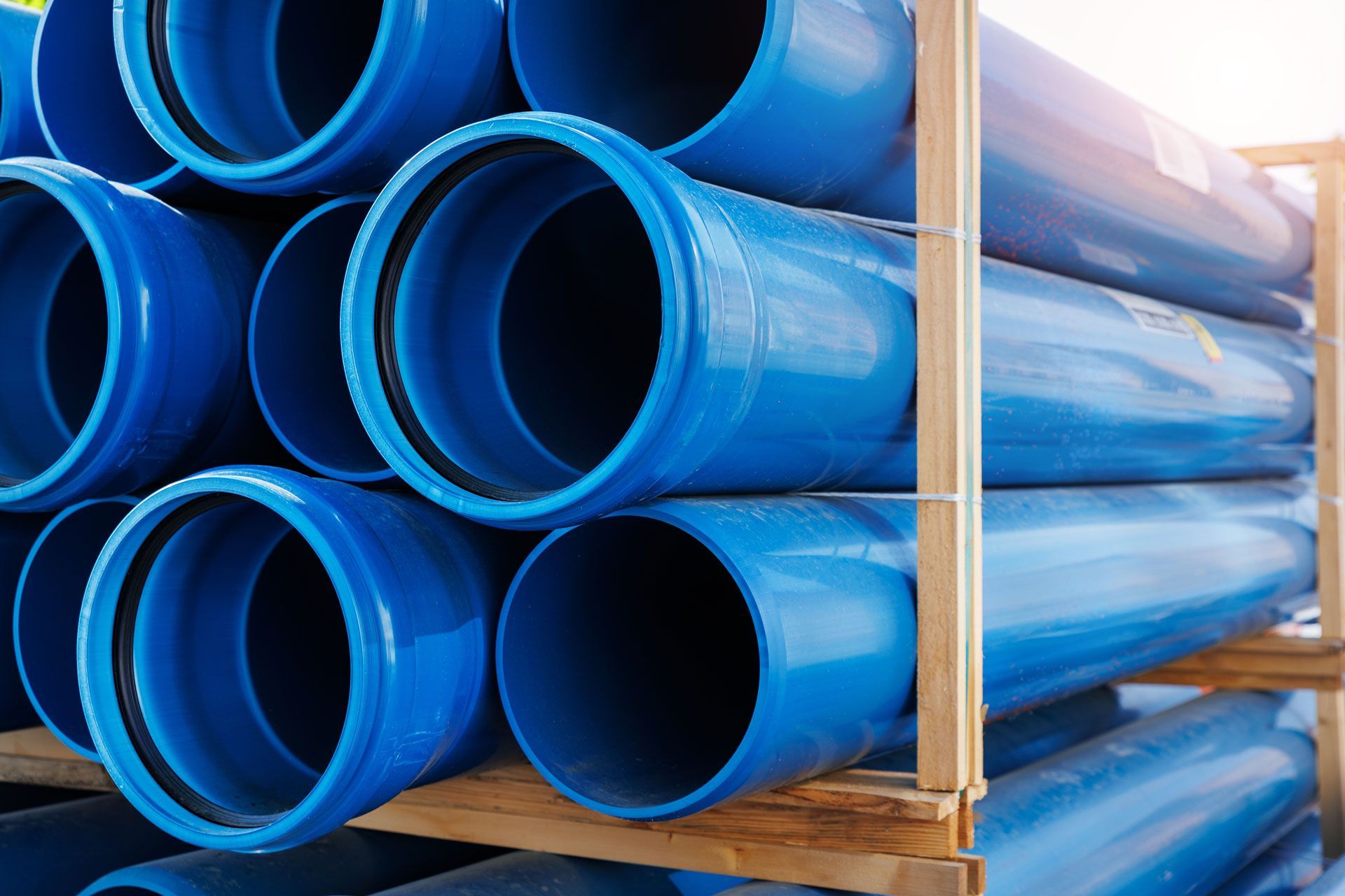 A stack of blue plastic pipes sitting on top of each other on a wooden pallet.