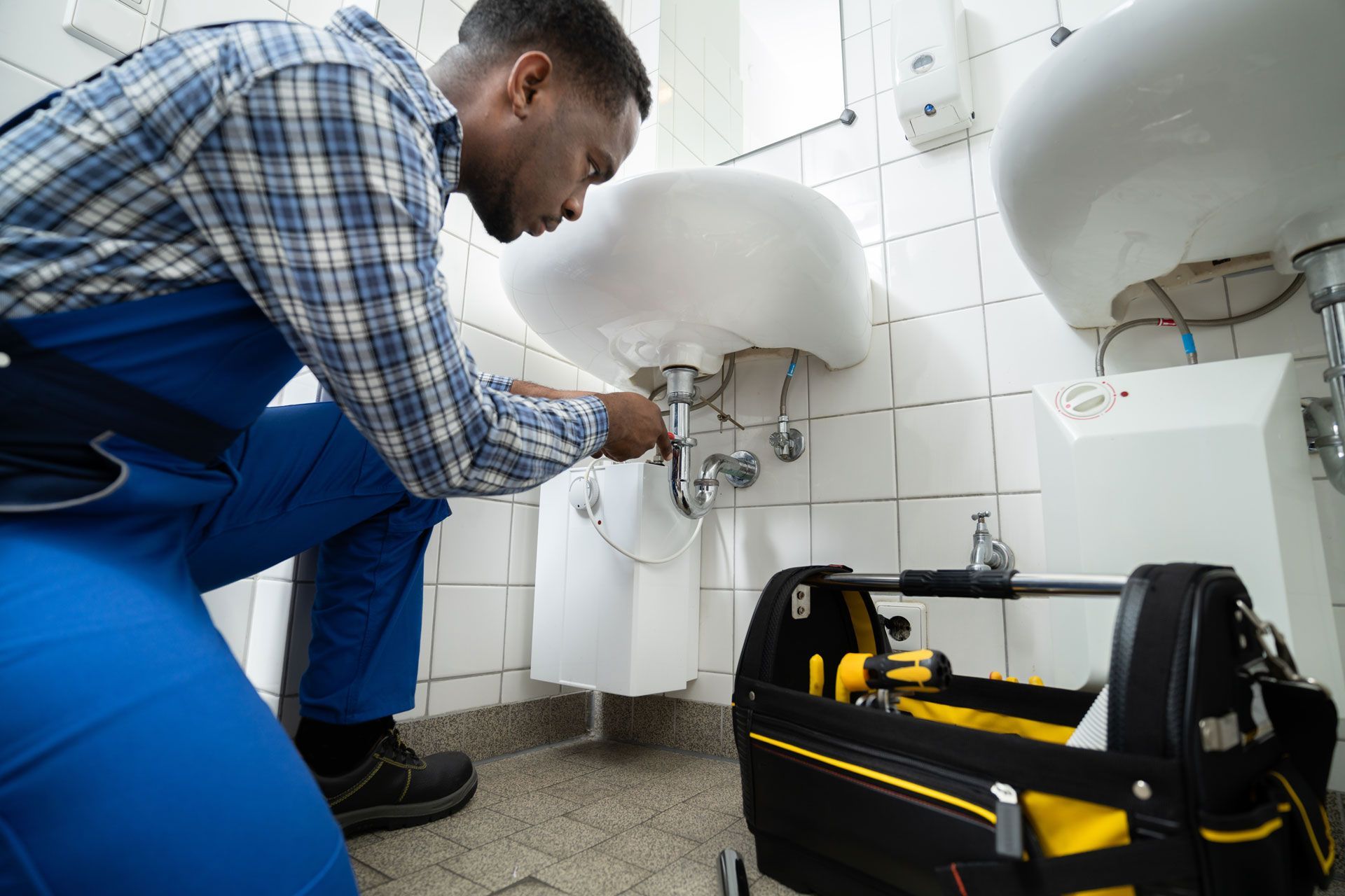 A plumber is fixing a sink in a bathroom.