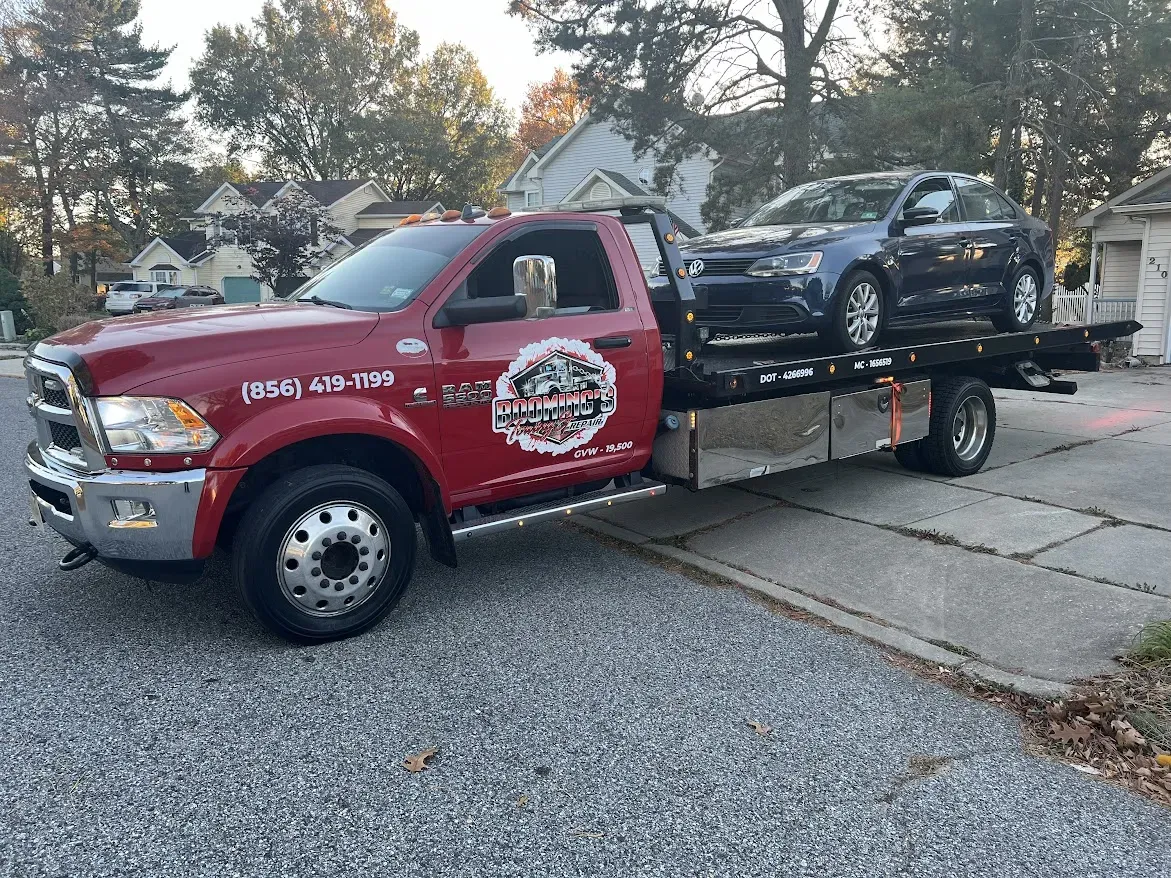 Red tow truck with a car on the flatbed in a residential area.