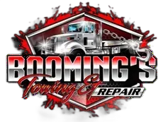 Logo for Booming's Towing & Repair, featuring a tow truck in front of a red and gray graphic design.