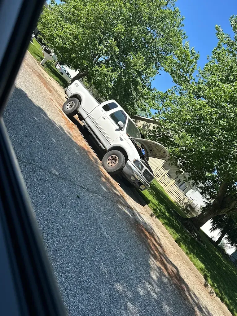 White pickup truck parked on a residential street on a sunny day.