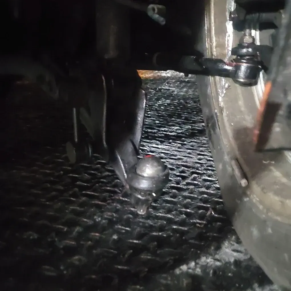 Black car suspension system with ball joints, on a metal surface.