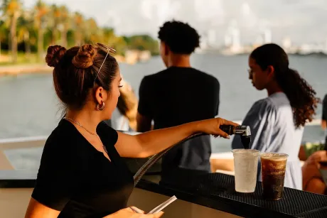 Bartender serving fresh drinks at the mojito bar during a Miami sunset boat cruise on Biscayne Bay.
