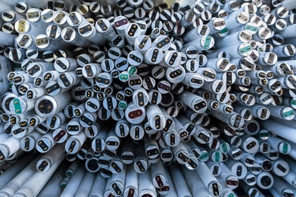 Eine helle, weisse Neonröhre beleuchtet eine strukturierte, dunkelgraue Wand mit einem rechteckigen Lichtstrahl.