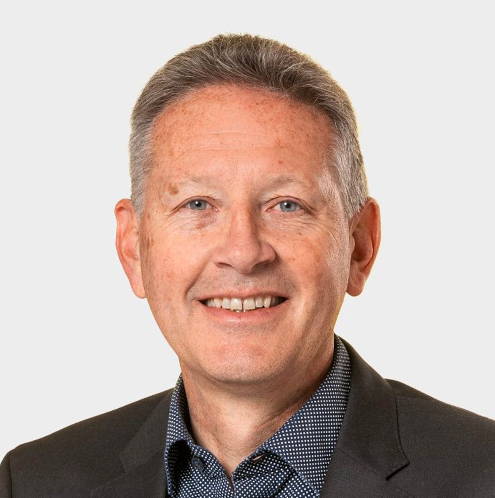 Ein Mann in Anzug und weissem Hemd lächelt in die Kamera