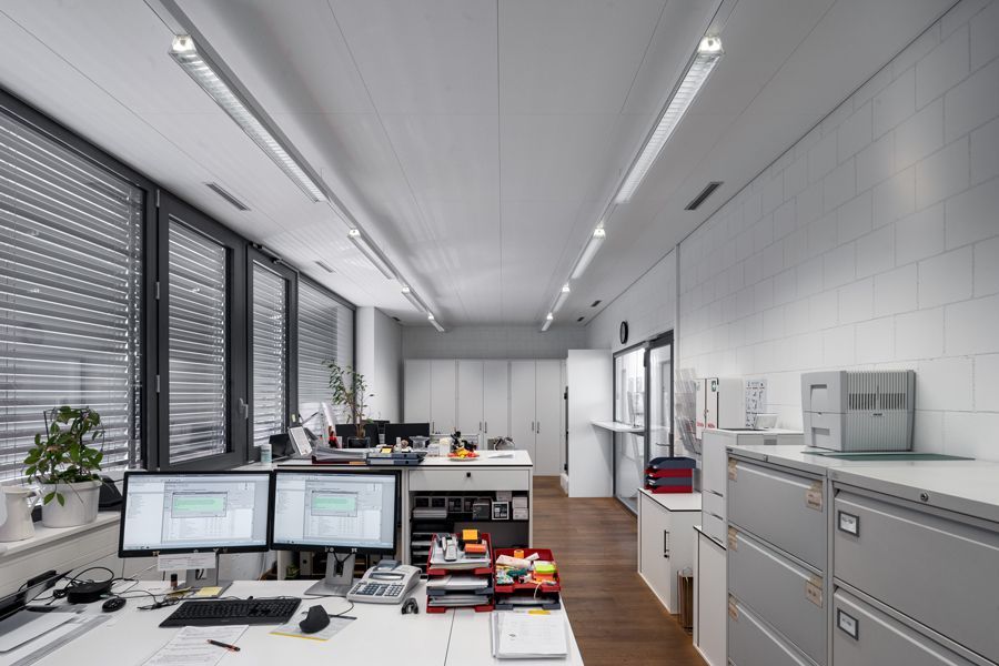 Ein grosses Büro mit vielen Fenstern und einem Schreibtisch mit zwei Computermonitoren darauf.
