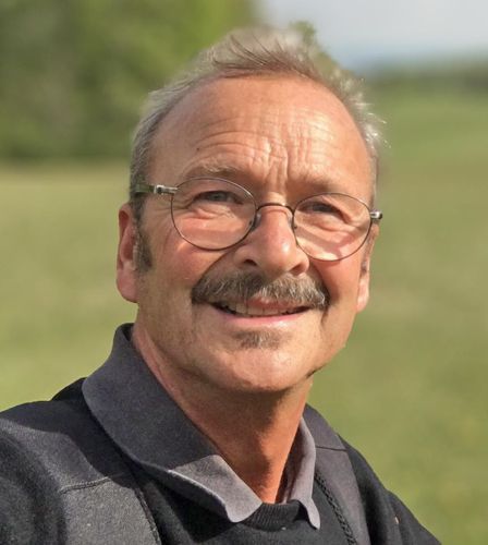 Ein Mann mit Brille und Schnurrbart lächelt in die Kamera.