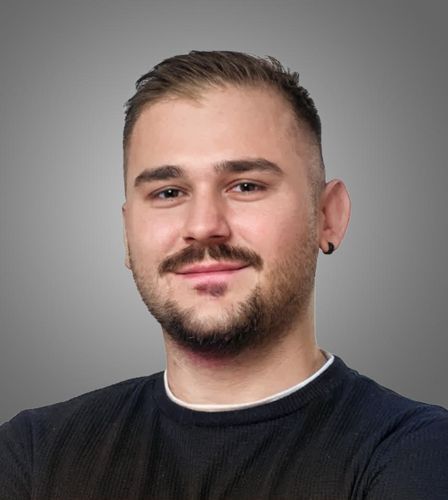 Ein Mann mit Bart und Schnurrbart lächelt in die Kamera.