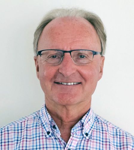 Ein Mann mit Brille und kariertem Hemd lächelt in die Kamera.