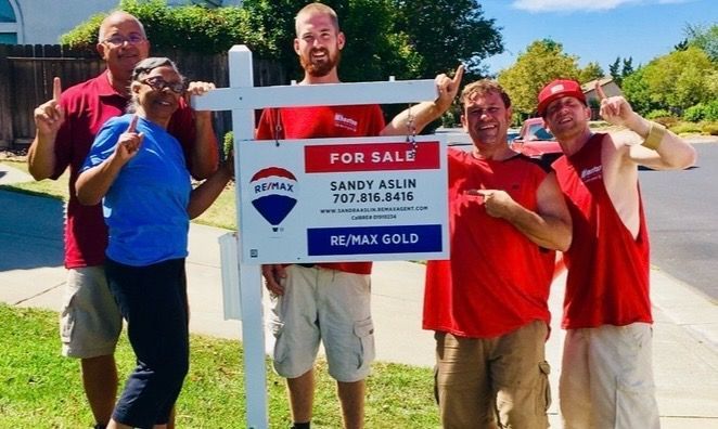 A group of people standing around a for sale sign