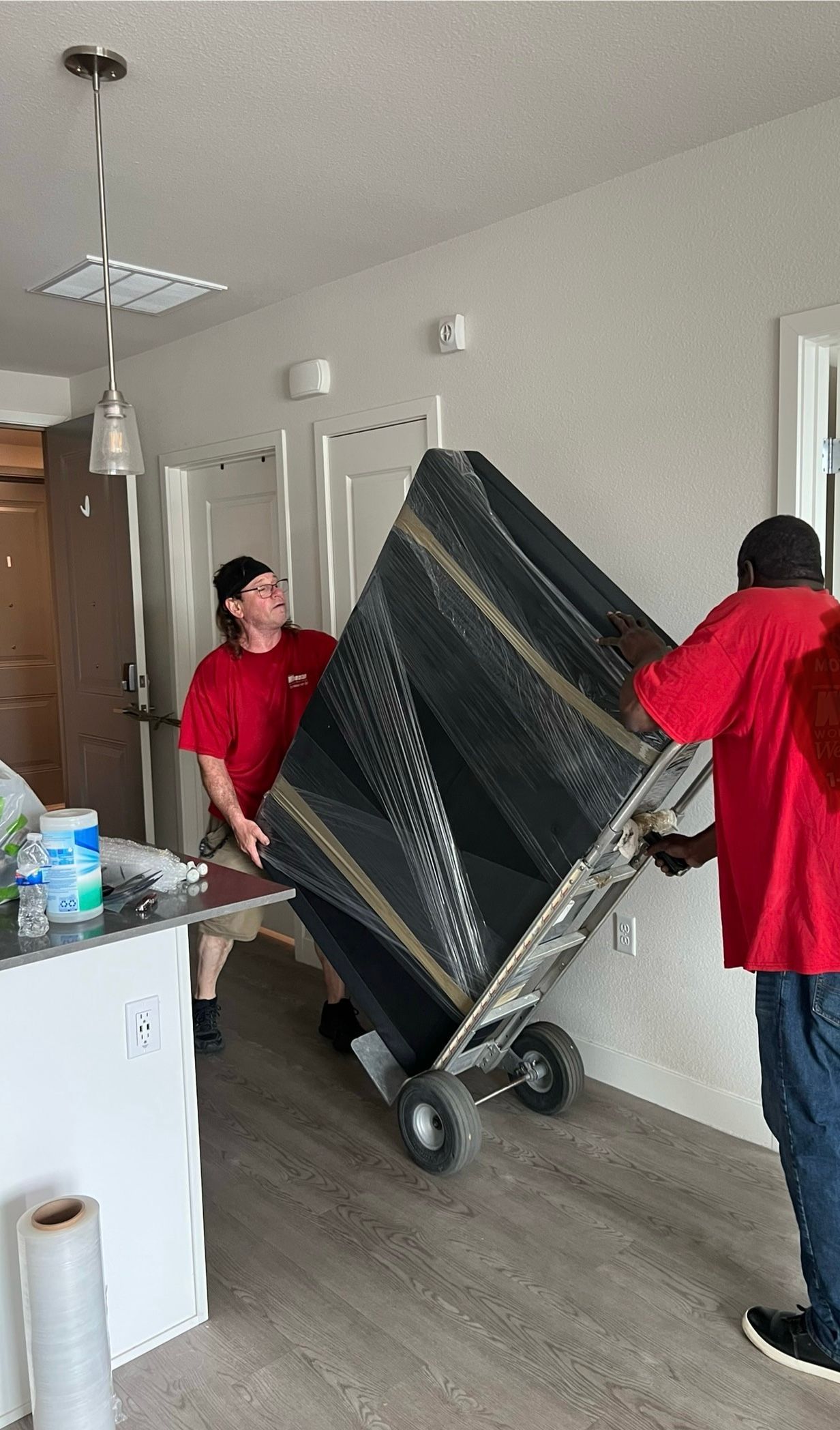 Two men are carrying a large piece of furniture on a dolly.