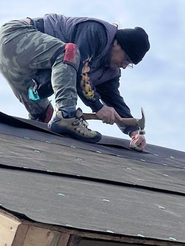 A man is working on a roof with a hammer.
