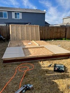 A wooden structure is being built in the backyard of a house.
