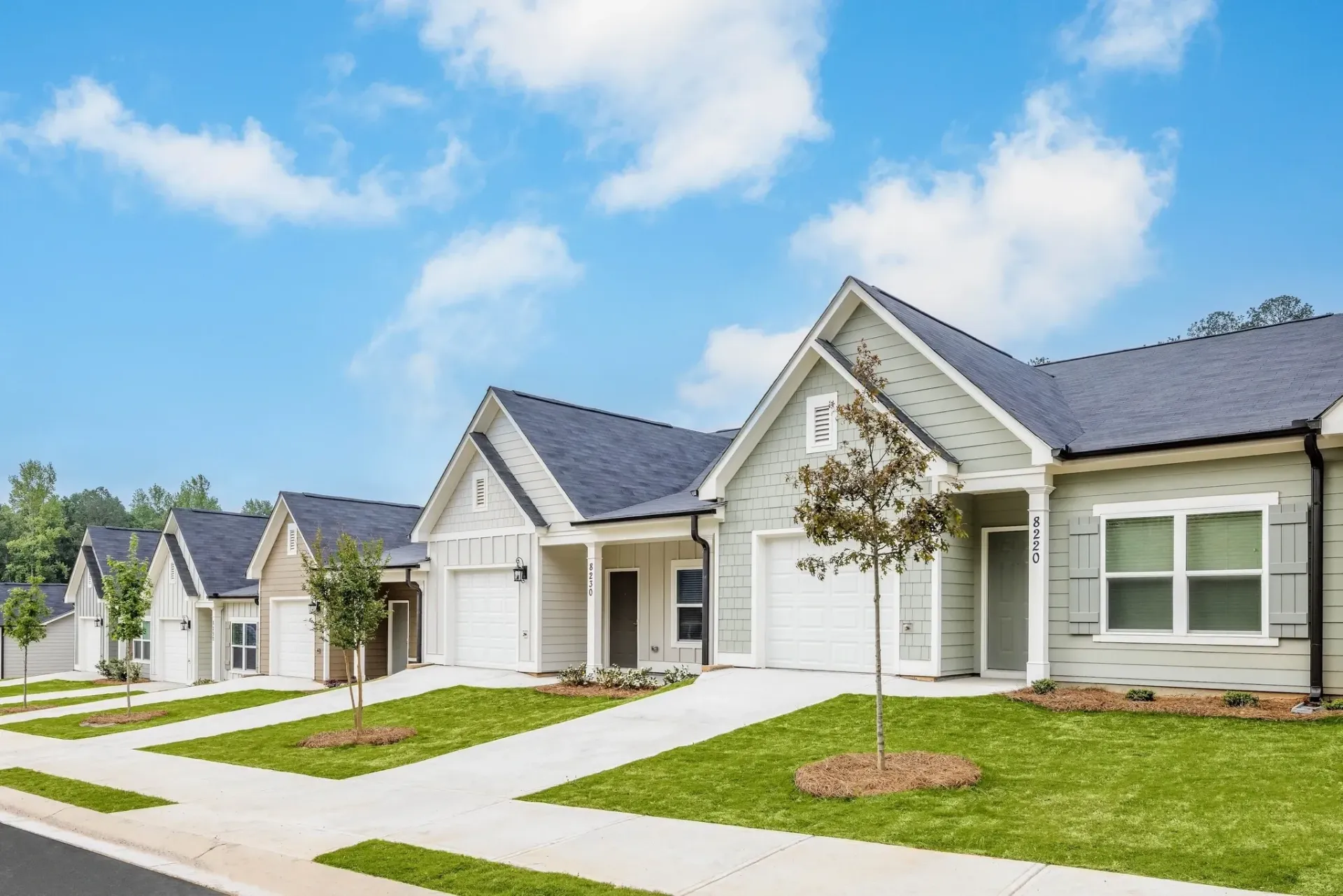 Row of single-family homes with manicured lawns and blue sky.