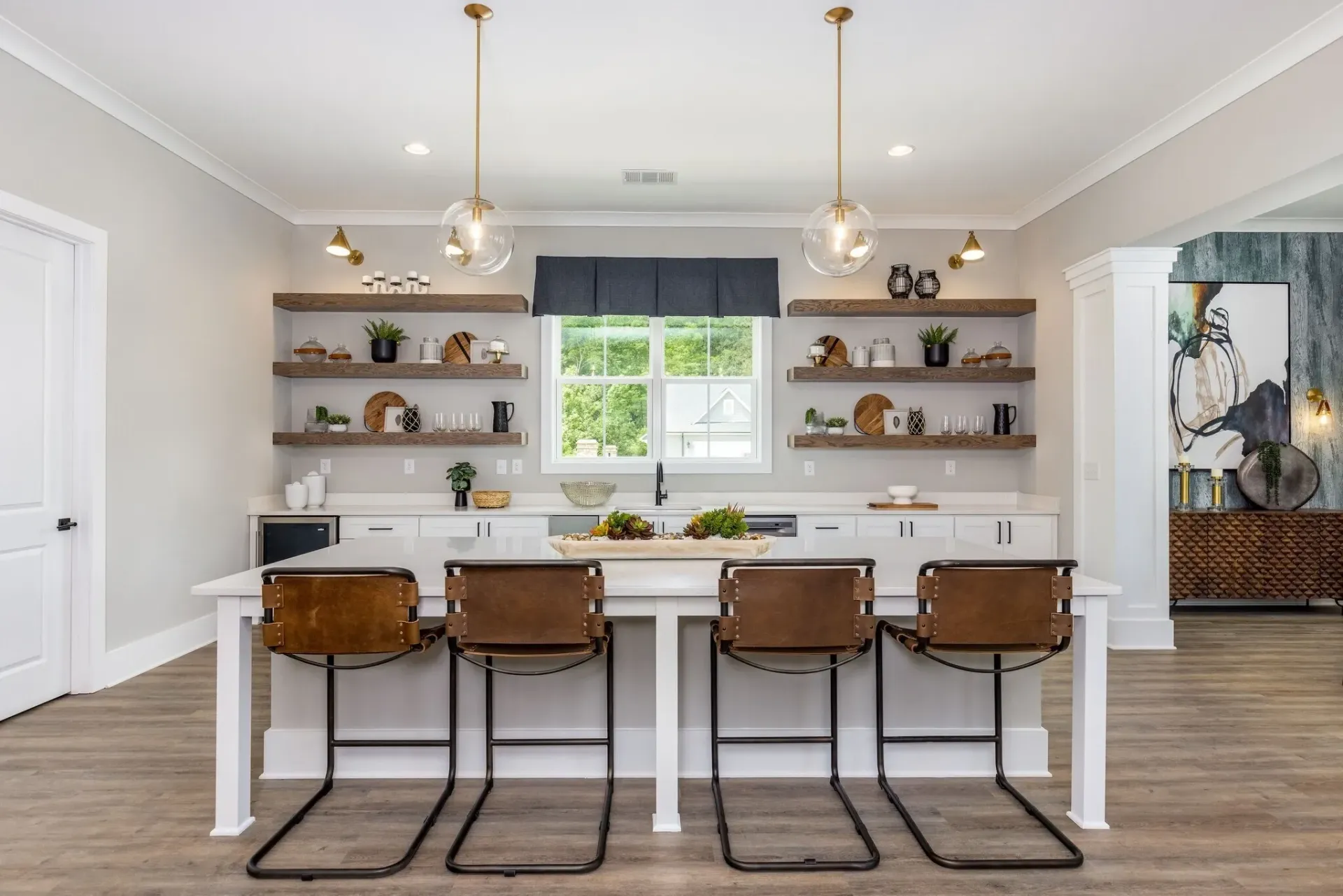 Modern kitchen island with four bar stools and view of open shelving and window.