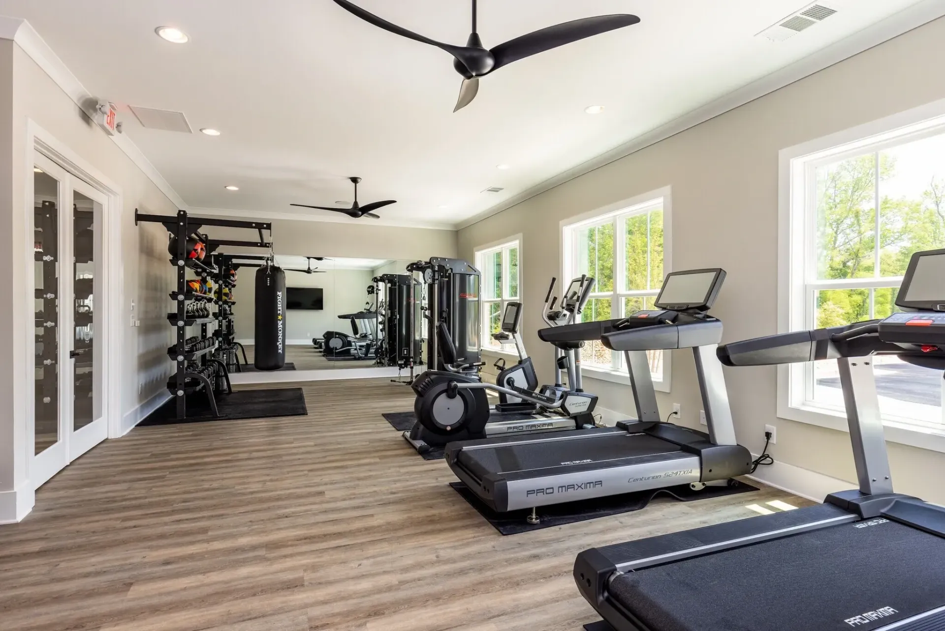 Gym with treadmills, ellipticals, weight racks, and punching bag.