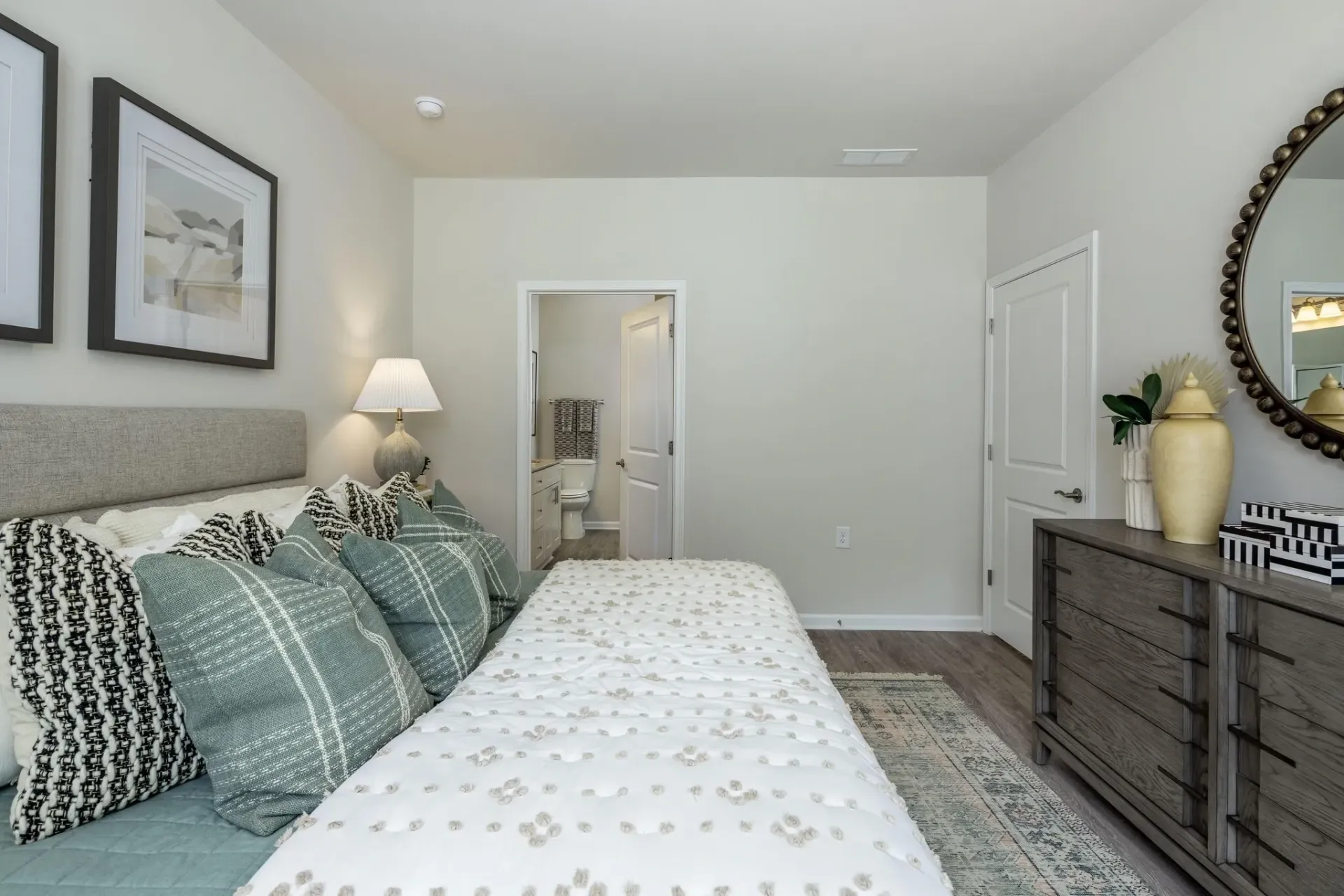 Bedroom with a large bed, dresser, and a doorway to a bathroom.