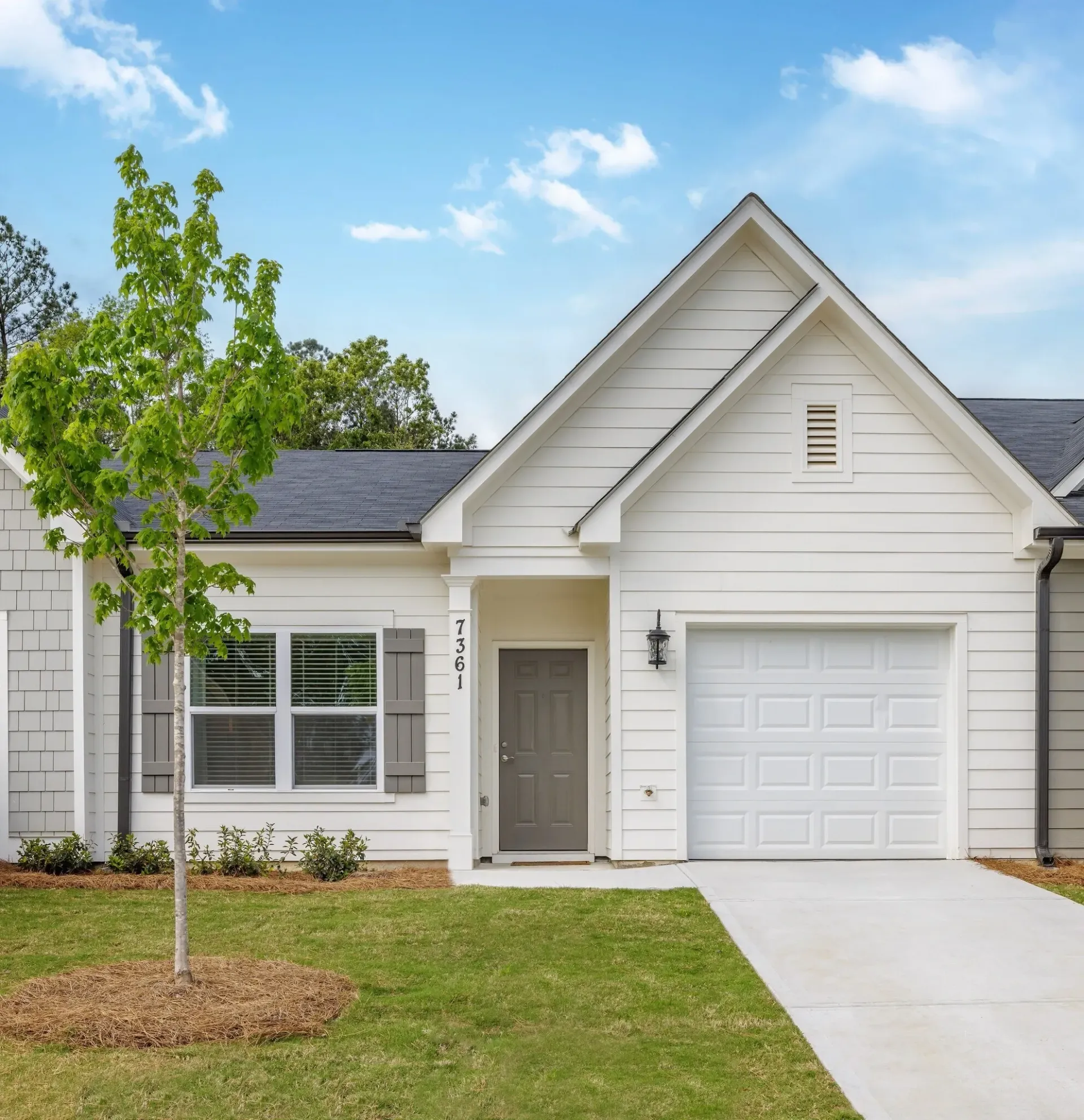 Exterior of a modern white house with a garage and a well-maintained lawn.