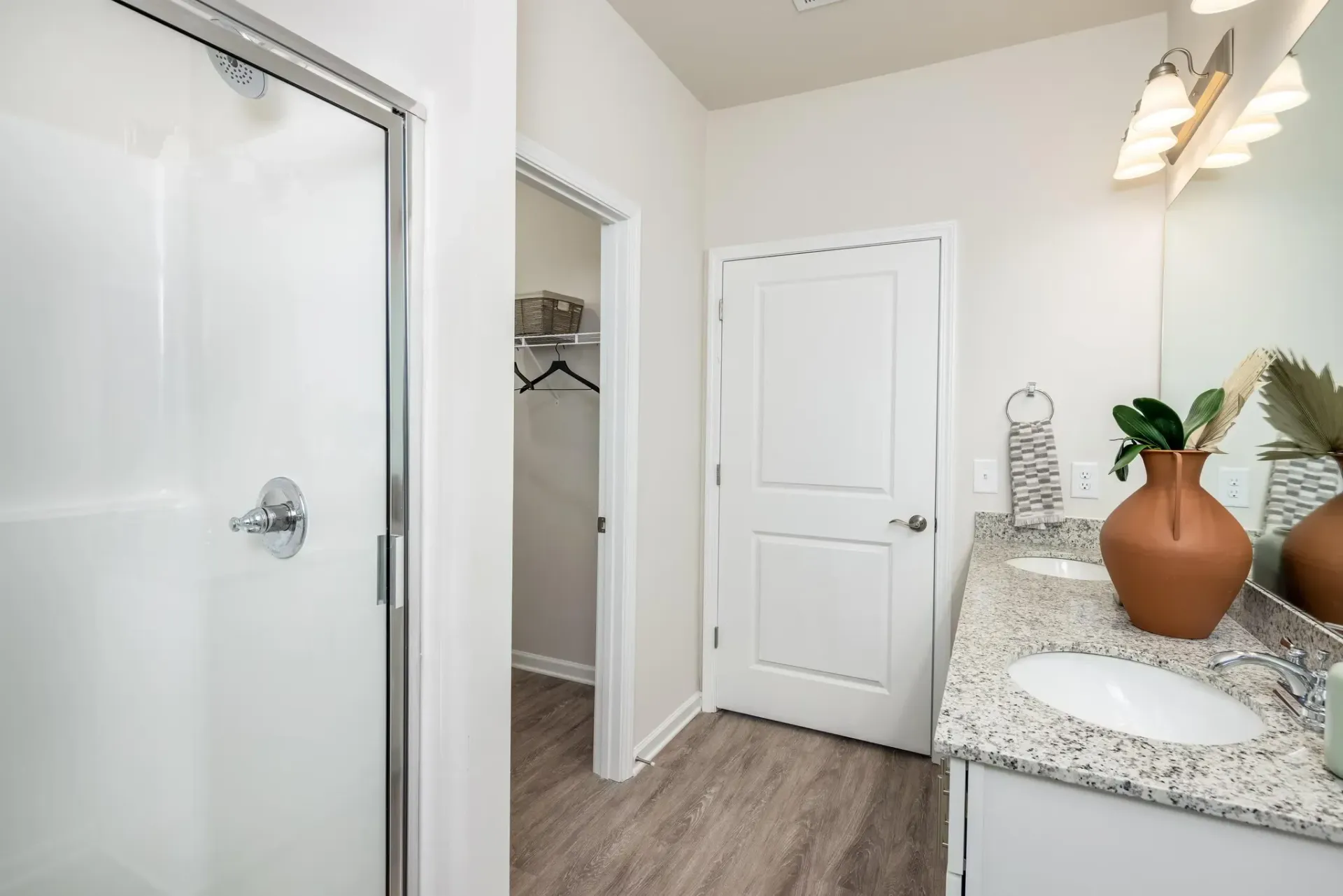 Modern bathroom with double vanity, granite countertops, a walk-in shower, and a closet.