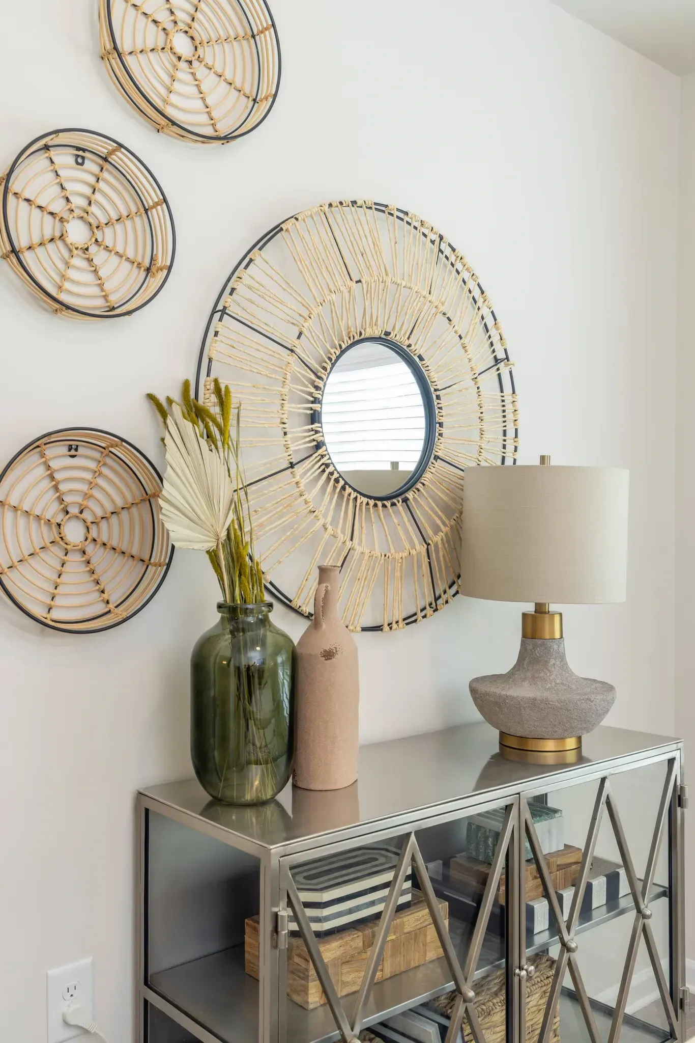 A decorative entryway console table with a lamp, vase, and wall decor.