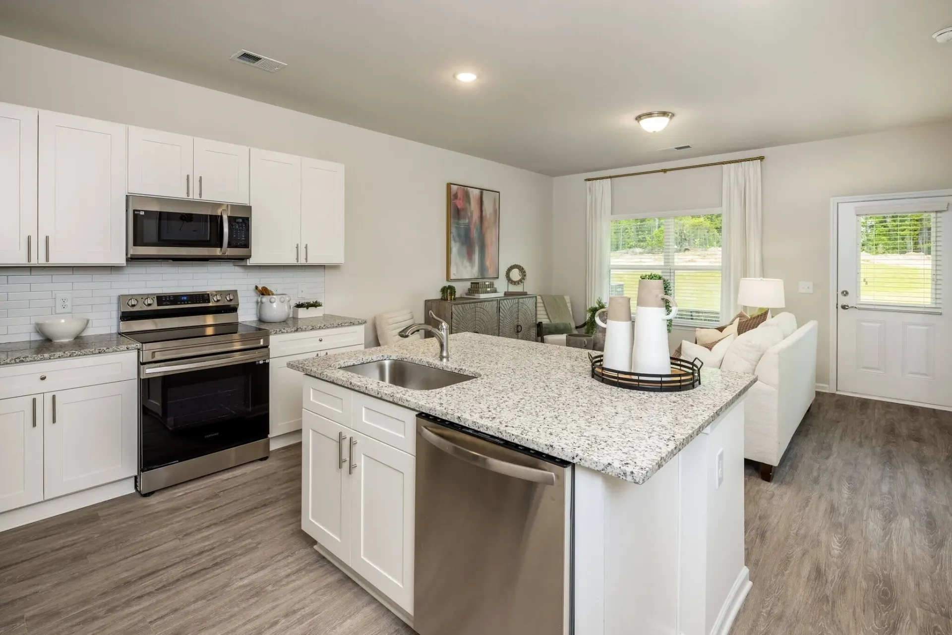 Modern kitchen with white cabinets, stainless steel appliances, and a granite island.