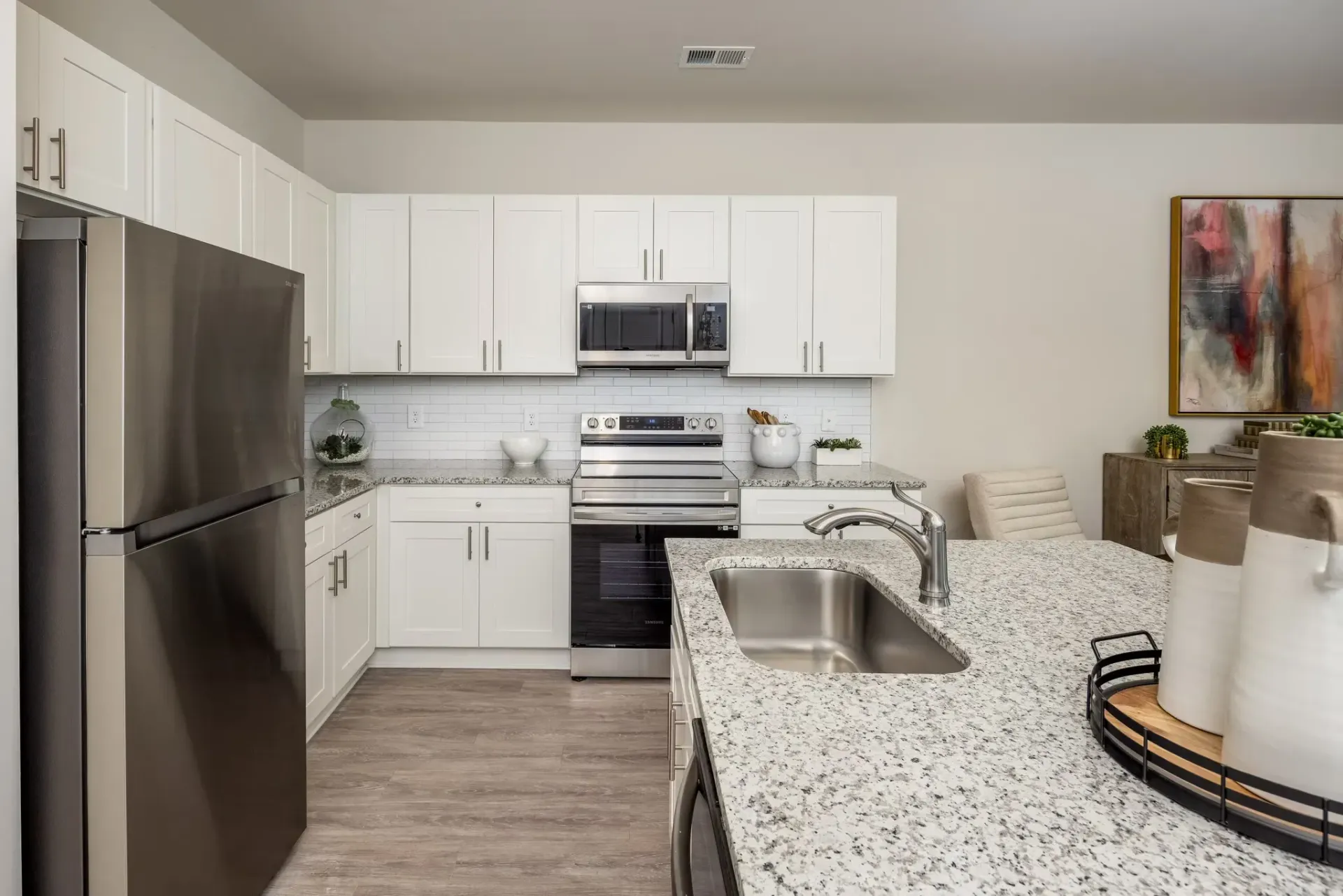 Modern kitchen with stainless steel appliances, white cabinets, and granite countertops.