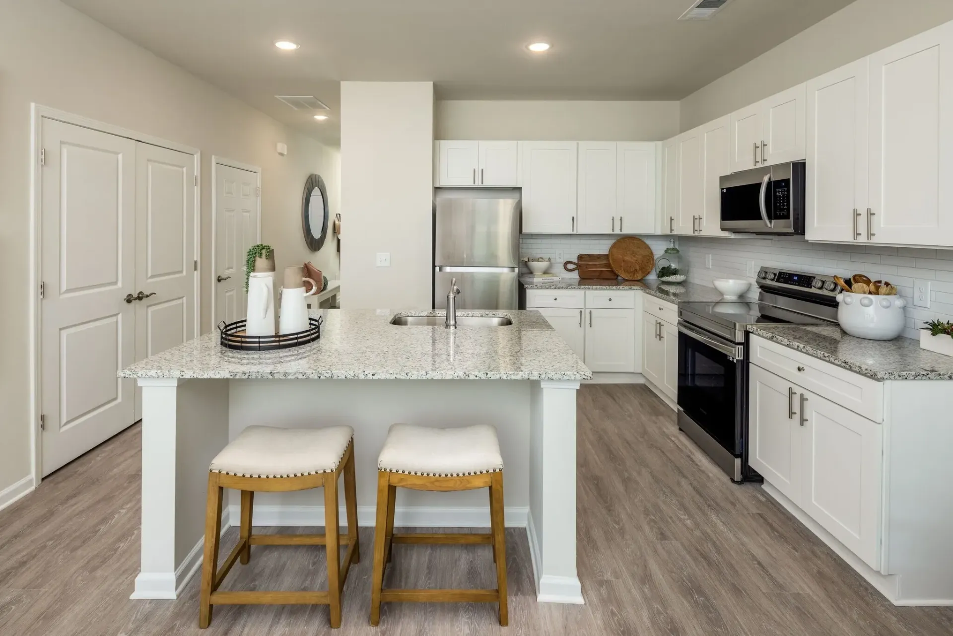 Modern kitchen with white cabinets, granite countertops, and stainless steel appliances.