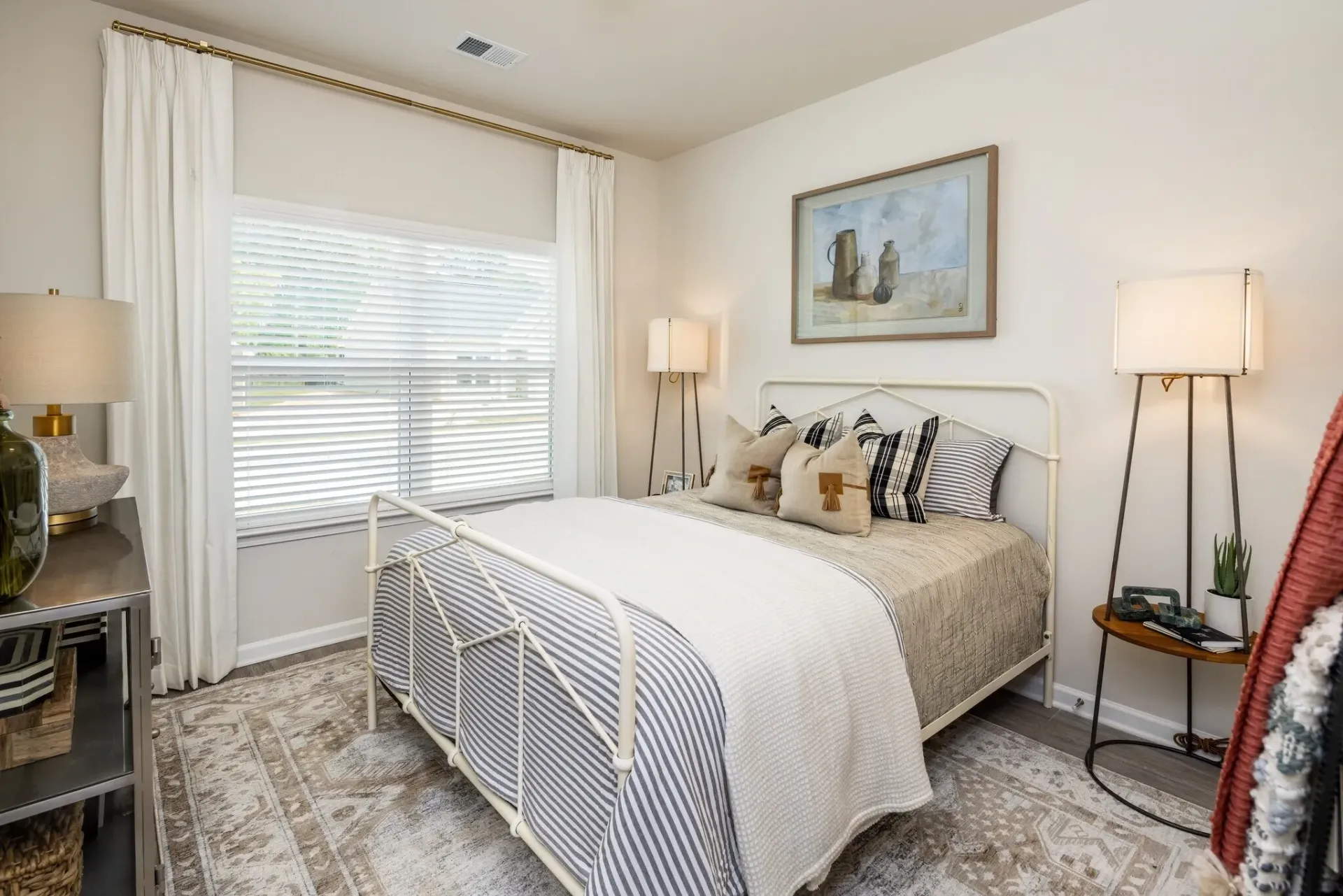 Bedroom with a queen-size bed, white linens, and striped pillows.