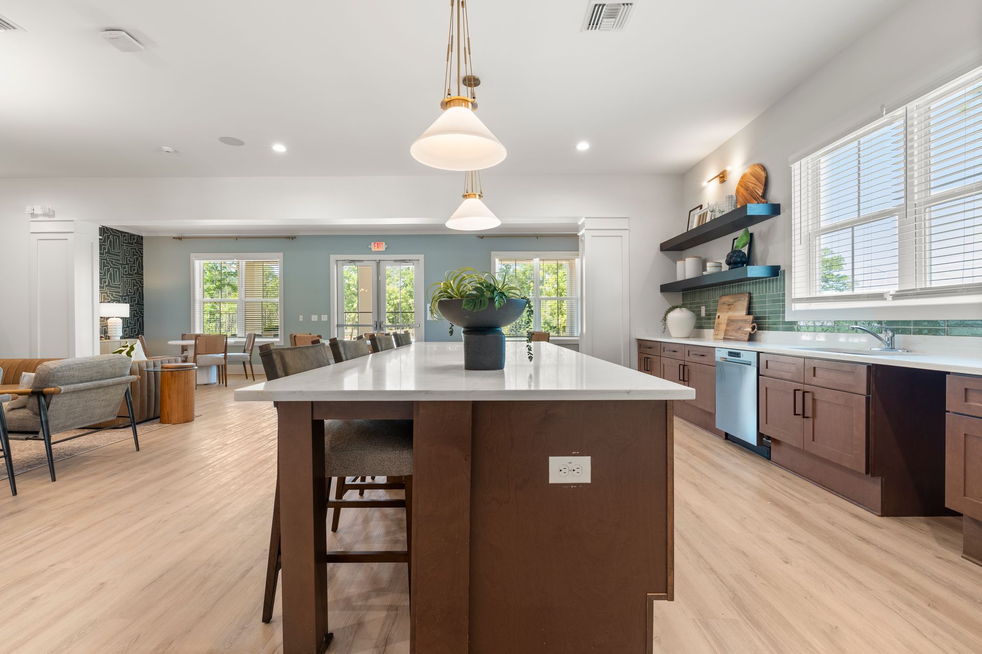Bright modern kitchen with large island, brown cabinets, light wood floors, and pendant lights