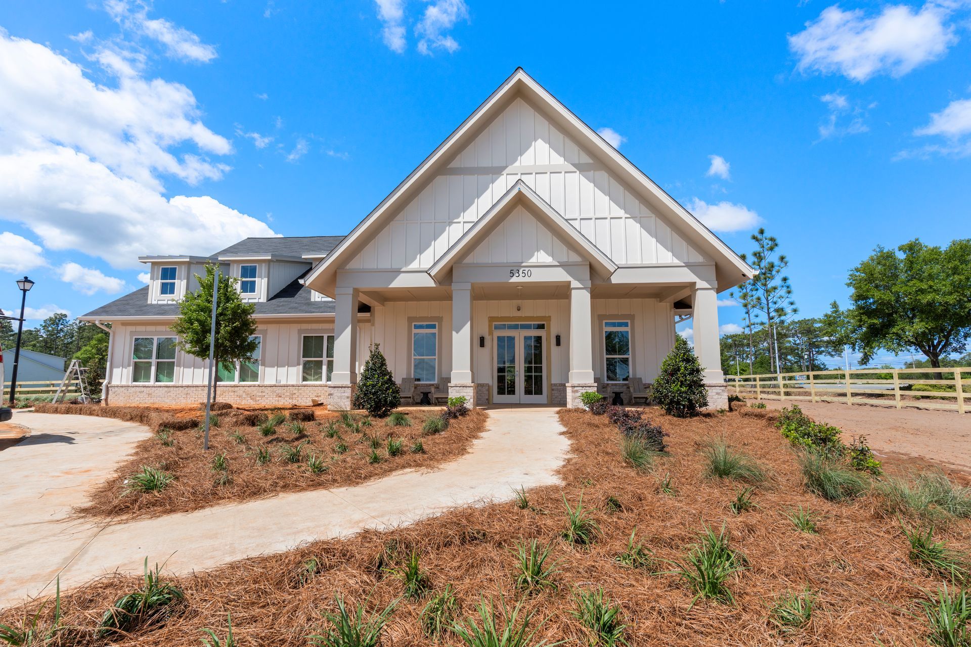 Modern tan house with white trim and a front walkway under a bright blue sky